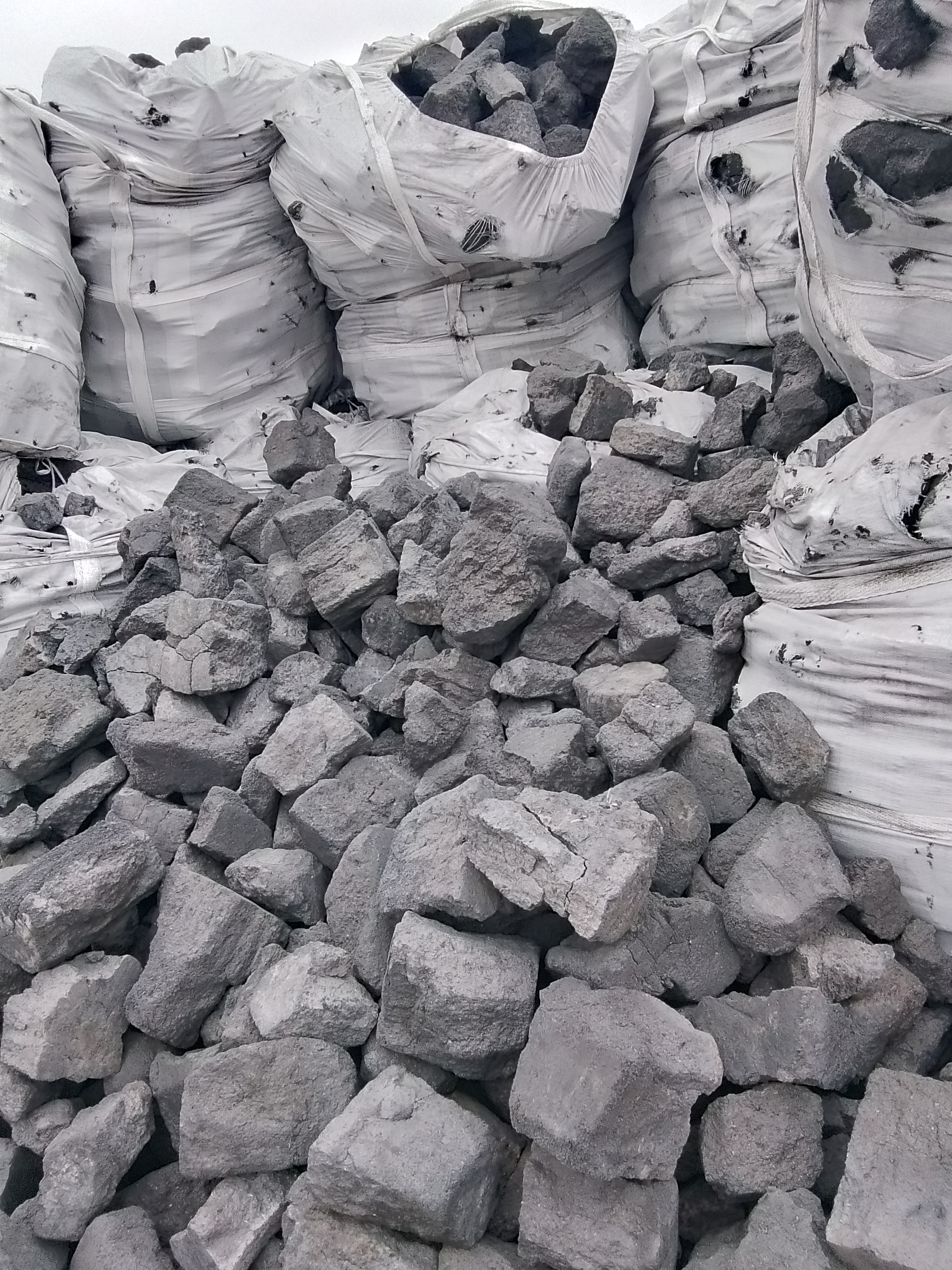 Trucks loaded with dark carbon material at an industrial yard